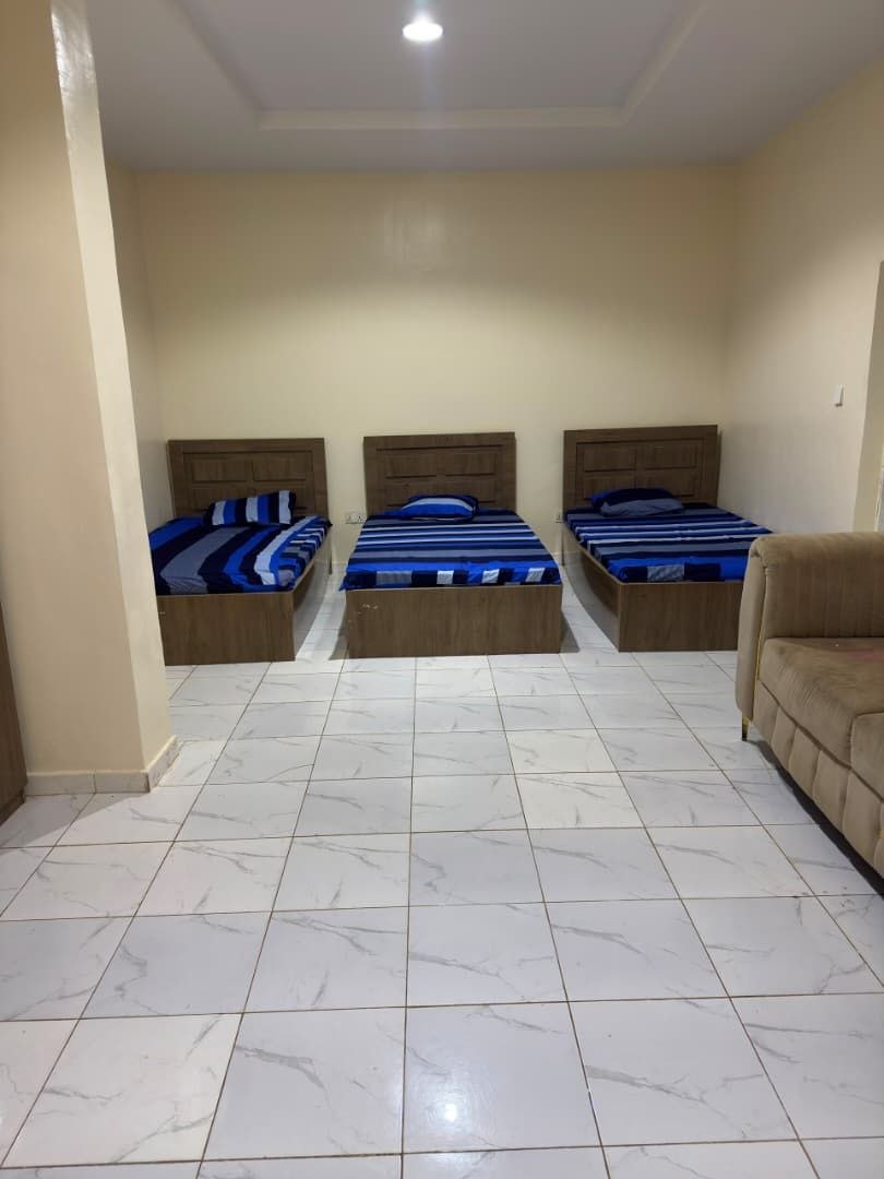 Three-bed room with made beds and marble tiled floor